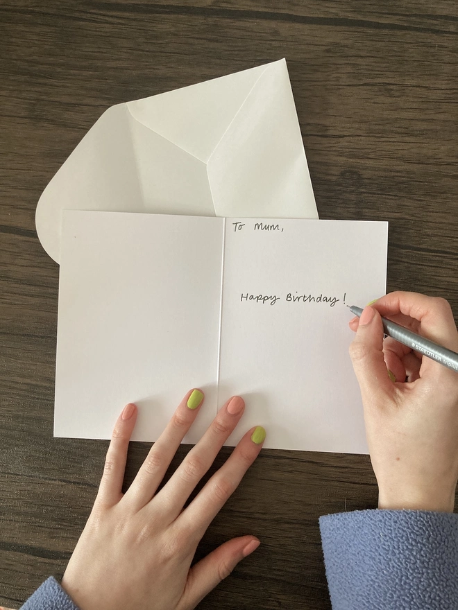 Hand writing out birthday message inside a card