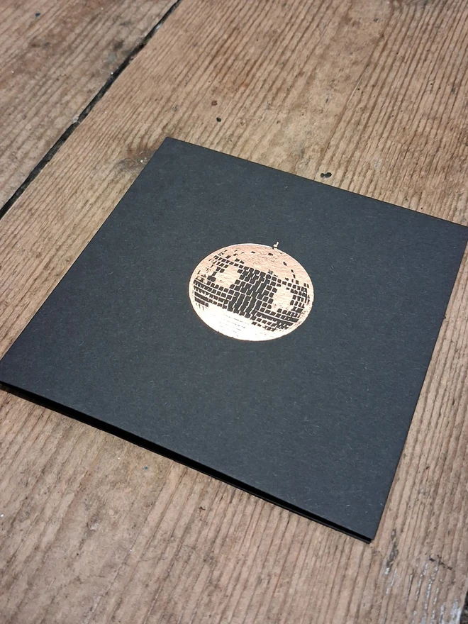 A greetings card printed in gold foil on black card with a picture of a disco ball