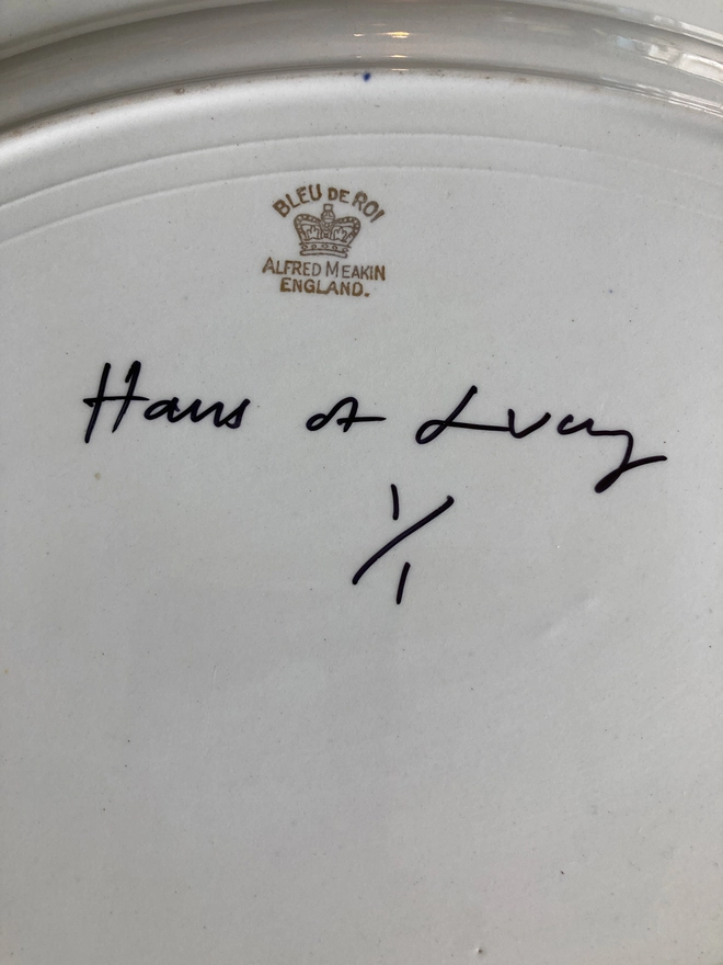 oval vintage china plate with a navy rim, featuring a navy blue 'Quavers' logo across the centre.