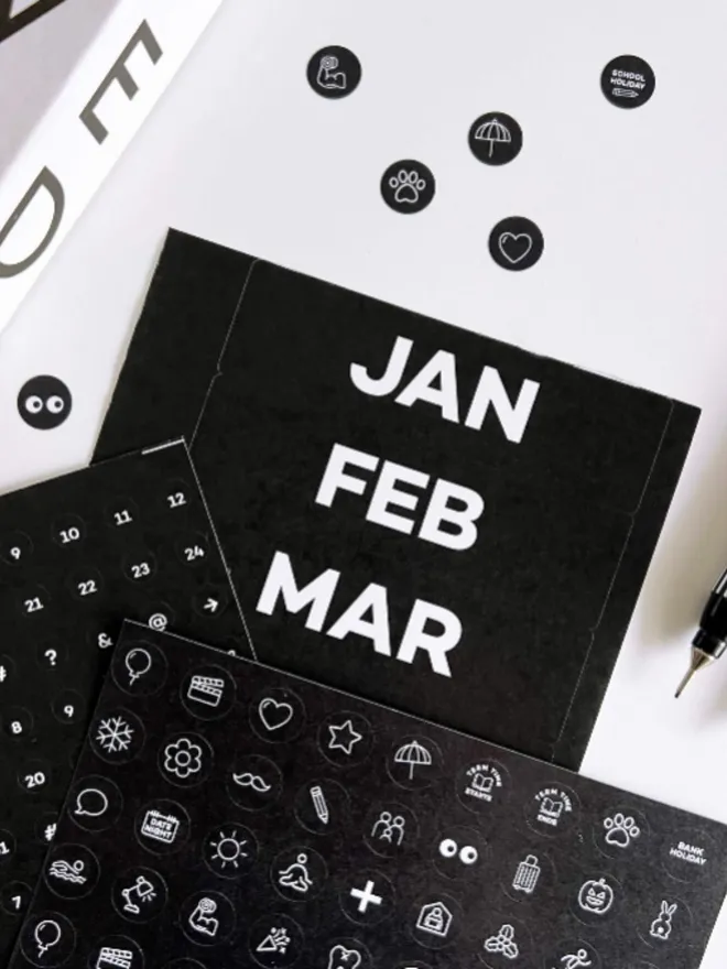 Black sticker sheets showing months, numbers, and white icon activity markers