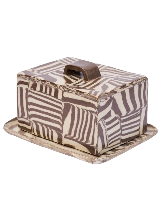 Striped Butter Dish, a colourful striped butter dish sitting on a white surface against a plain backdrop. 