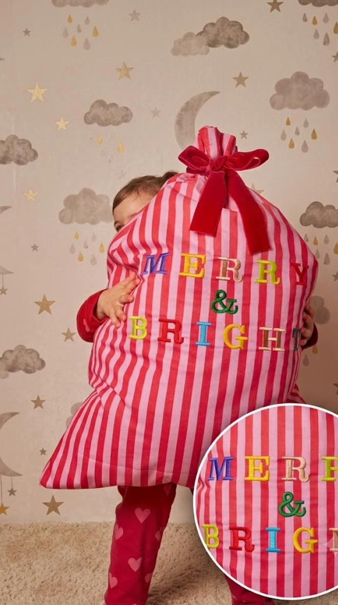 little girl holding Merry & Bright sack 