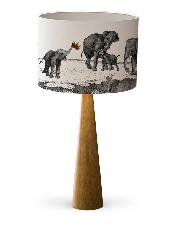 Drum Lampshade featuring elephants with a white inner on a wooden base on a white background