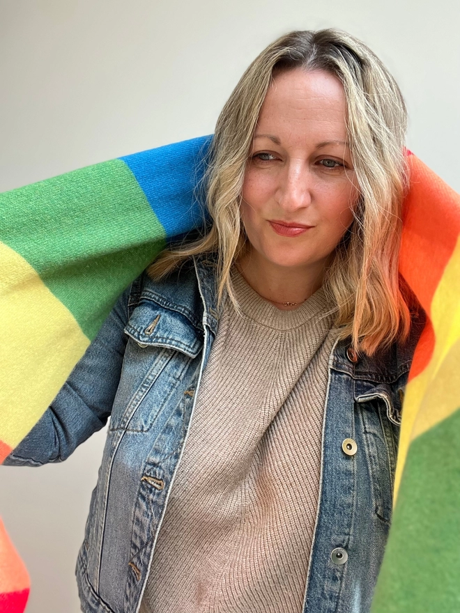 Rainbow stripe scarf shown  being draped over shoulders