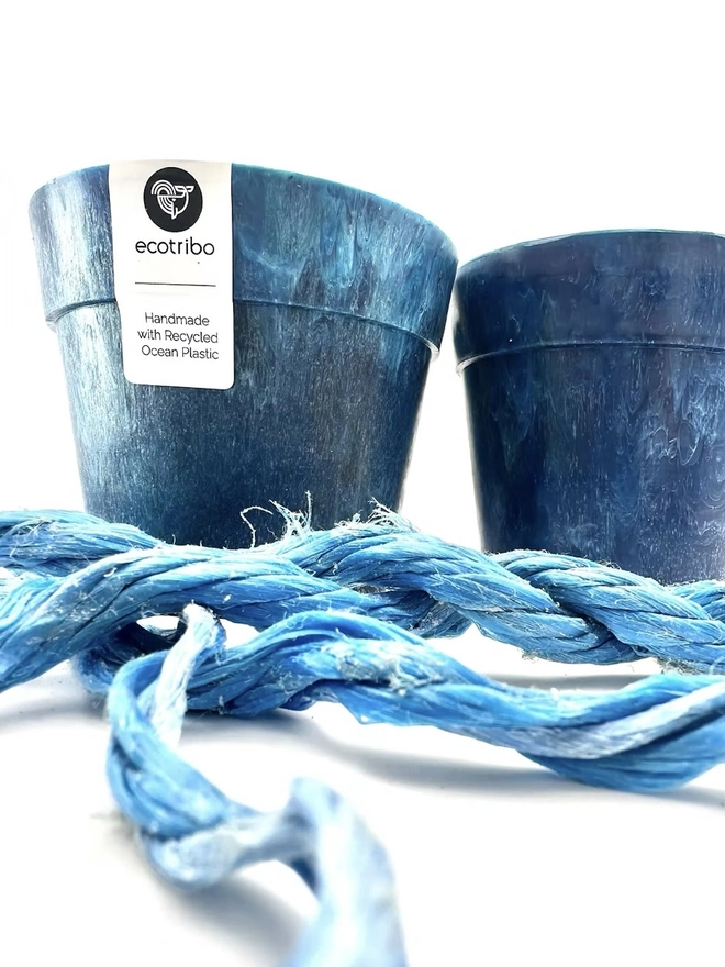 Small Blue Ocean Plastic Plant Pot , a collection of blue recycled pots sitting on a white surface against a plain backdrop. 