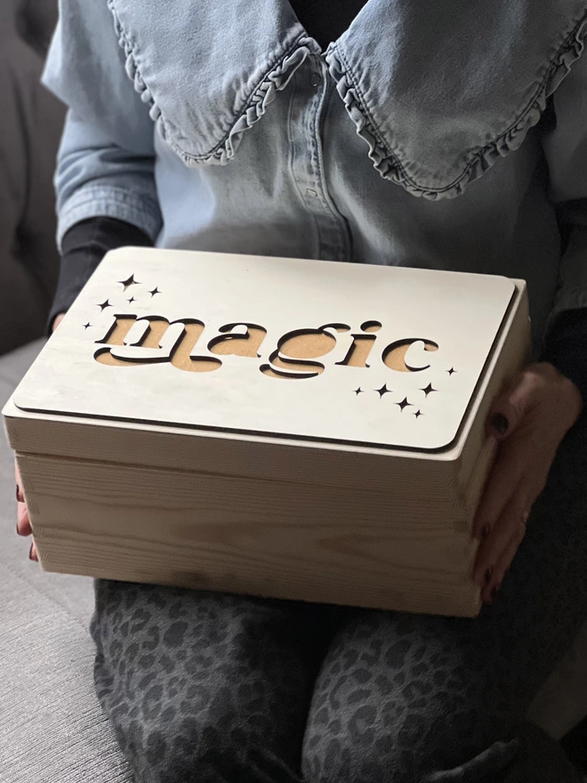 wooden box with magic carved onto it and mustard linen fabric showing through