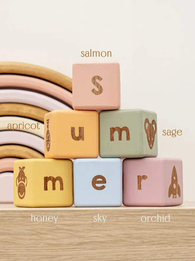wooden baby letter blocks. a selection of square wooden blocks with engraved letters and illustrations, in various colours. 