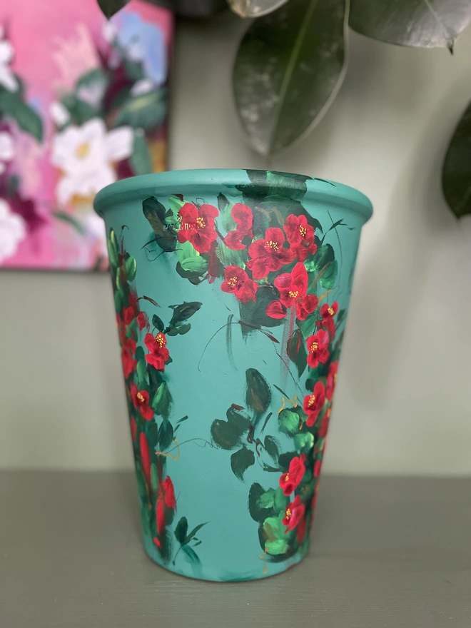 Hand painted tall deep green plant pot adorned with bright red quince flowers