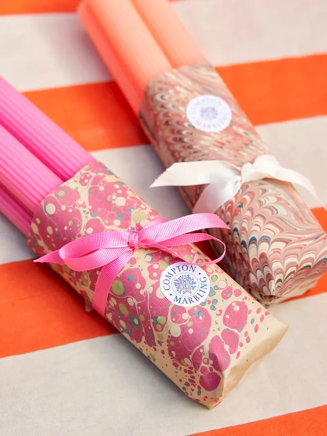 two sets of scalloped dinner candles, each with a marbled paper wrapping and ribbon