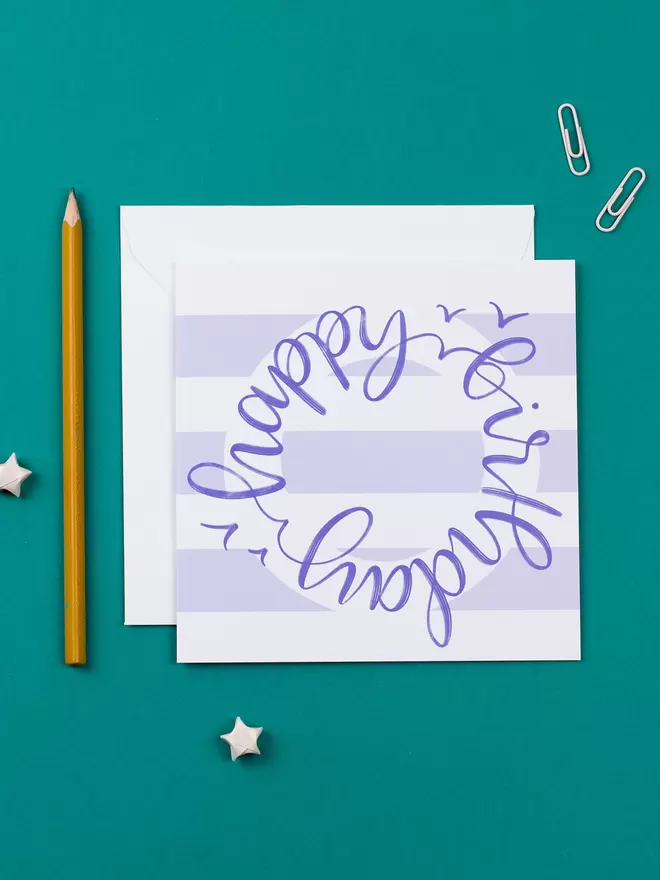 A lilac-and-white striped card which reads 'happy birthday' in purple hand-lettered circular scrip