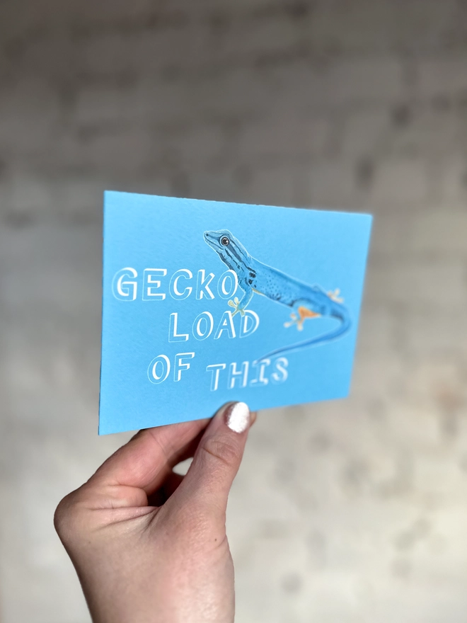 a bright blue greetings card featuring an illustration of a blue gecko with the text “GECKO LOAD OF THIS”