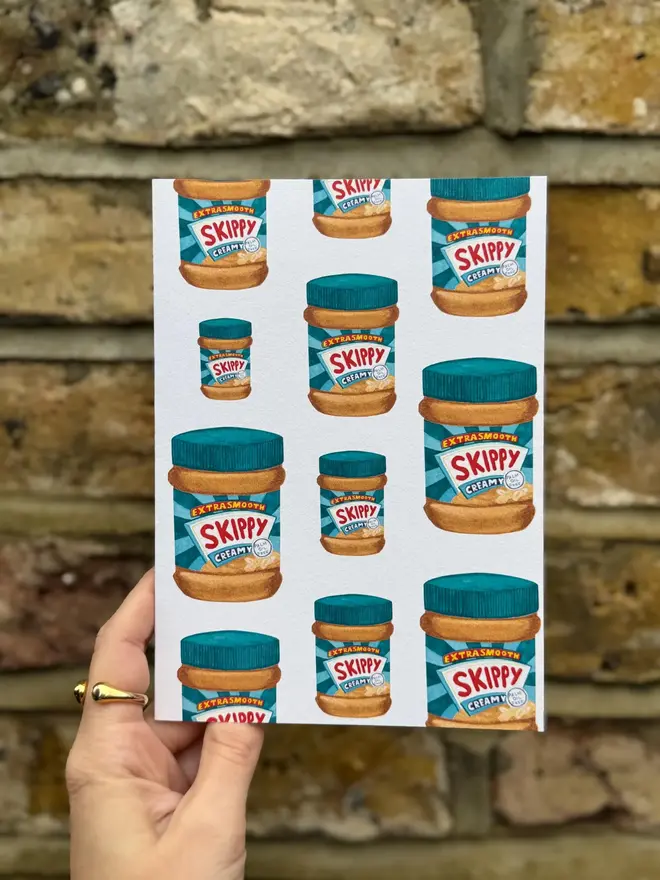 peanut butter jars illustrated card. card photographed against brick wall backdrop.
