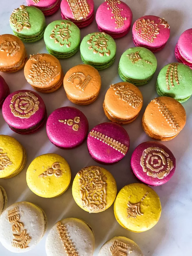 colourful macarons with gold mehndi henna designs painted on against white background
