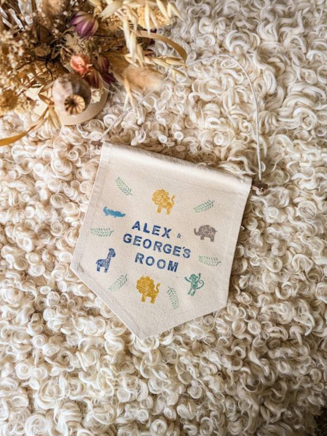 customised kids' bedroom cotton wall hanging. a banner with printed animals hanging on a bedroom wall.