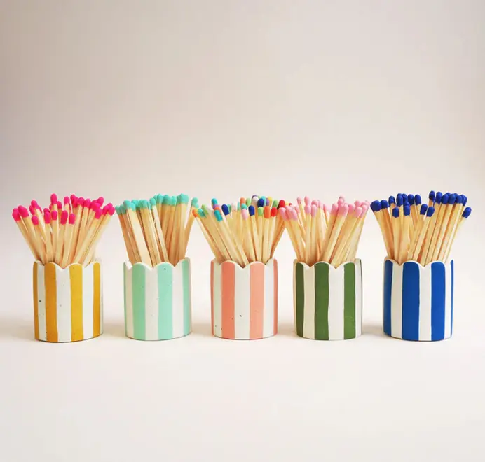 Stripy Match Stick Holders. Coloured matchsticks in a striped, scalloped matchstick holder on a white background.  