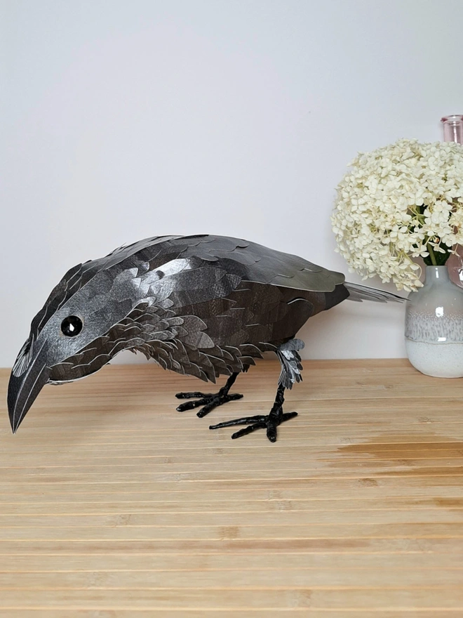 side view of a raven sculpture, made from handprinted papers