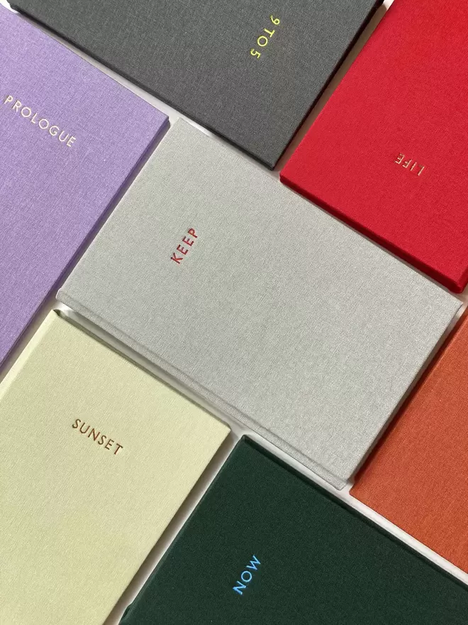 An array of handmade bespoke personalised pocket sized notebooks in various coloured book cloths