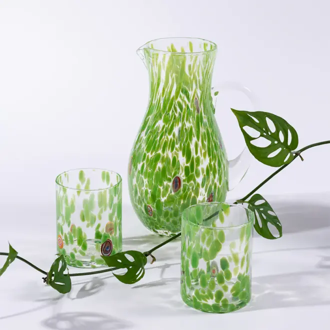 green glass jug with two glass tumblers and a plant