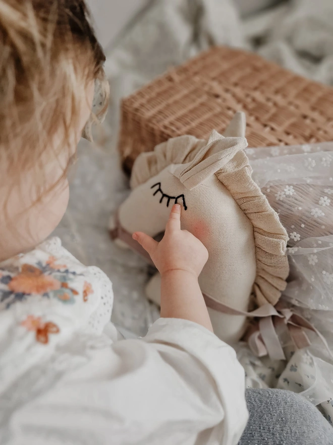 Horse Baby Rattle Toy, a child with a horse baby rattle toy in a bedroom surrounded by other bedroom accessories. 