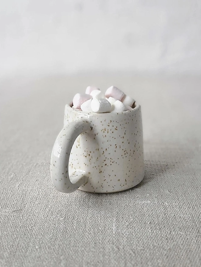 Classic Ceramic Espresso Mug, a colourful ceramic espresso mug sitting on a plain surface against a white backdrop. It is accompanied by a group of marshmallows. 