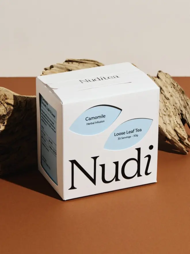 white box of camomile tea with pale blue design next to log