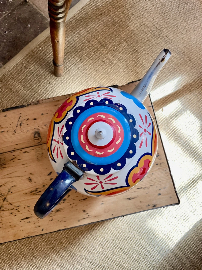 Lid of white vintage teapot, hand painted with a blue and pink striped pattern.