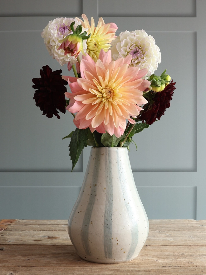Large Handmade Ceramic Stoneware Vase in Blue and White Stripe sat on a wooden surface holding a bouquet of pink, yellow, white and red flowers.