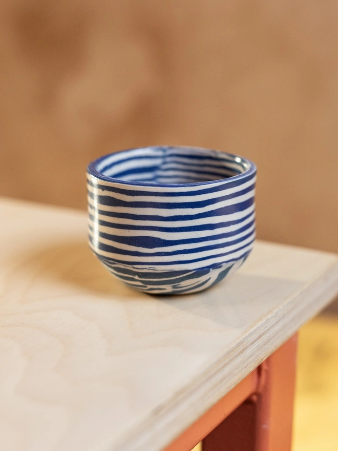 Striped Coffee Cup, a striped coffee cup sitting on a white table top. 