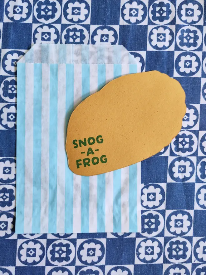 hand painted pain au chocolat, cut out paper shape. with blue and white striped paper bag
