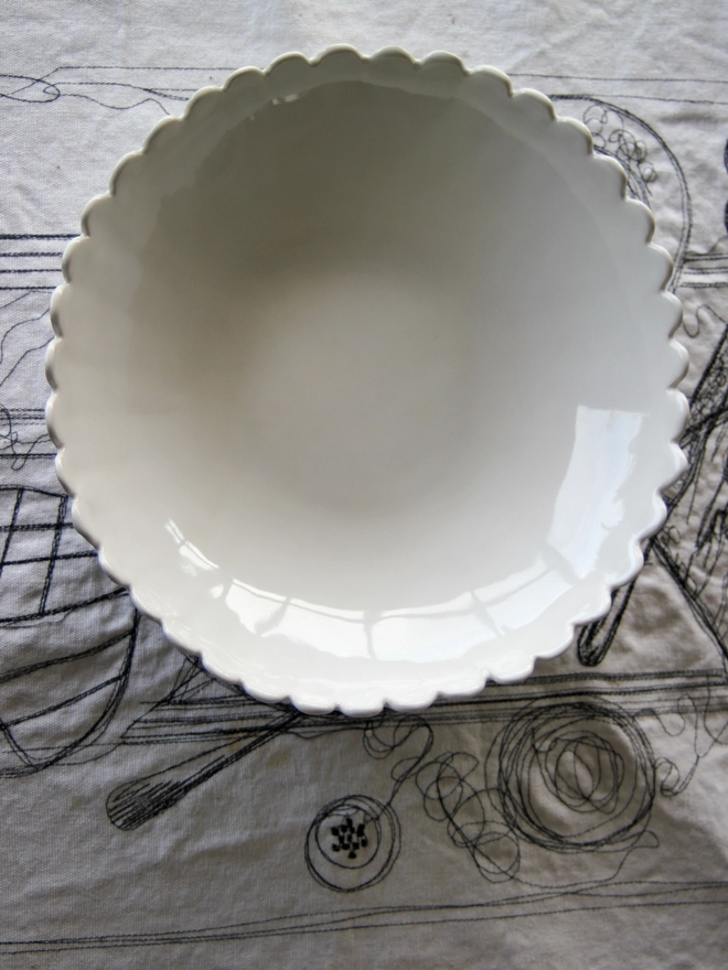 looking into the surface of a scalloped edge white handmade serving bowl 
