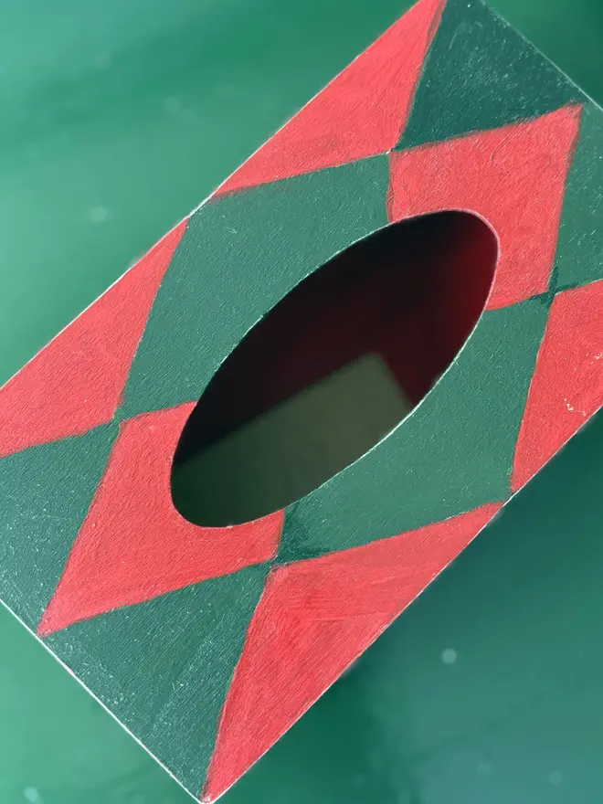hand-painted harlequin tissue box. a tissue box in red and green painted harlequin pattern.