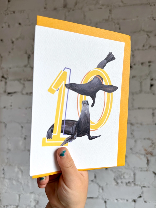 Number ten card with yellow numbers with sea lion illustrations and a yellow envelope