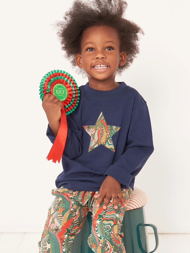 A 4 year old boy wearing a navy blue christmas tee with a Liberty star print star sewn on the front