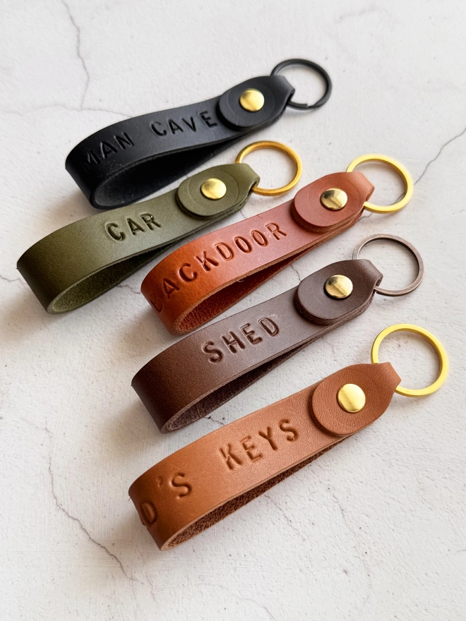 tan, olive, black and brown leather loop keyrings personalised with words such as shed, car and mancave.
