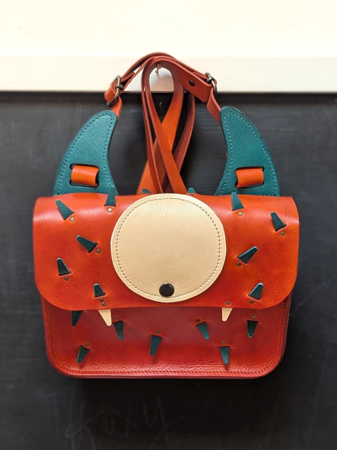 Leather monster backpack in orange and blue front view.