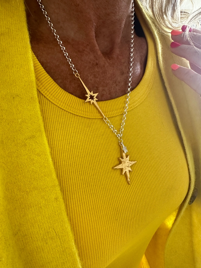 model wears gold north star and overlaid mini star in silver on a sterling silver chain, with linked supernova charm in gold 