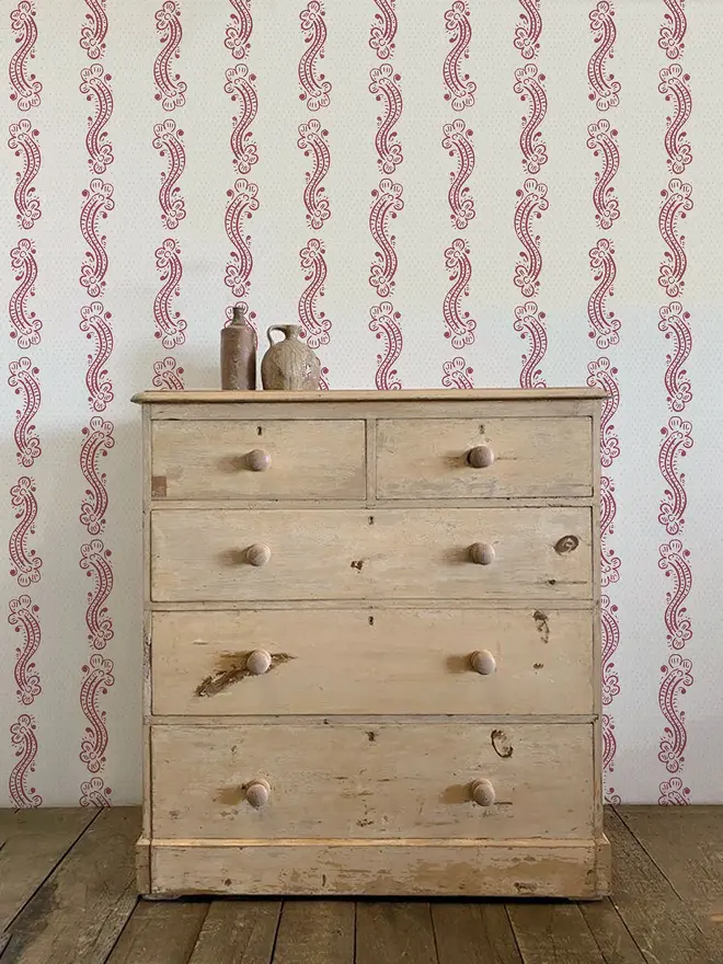 cedilla illustrated patterned wallpaper. a white background wallpaper with burgundy squiggle patterns on a wall.
