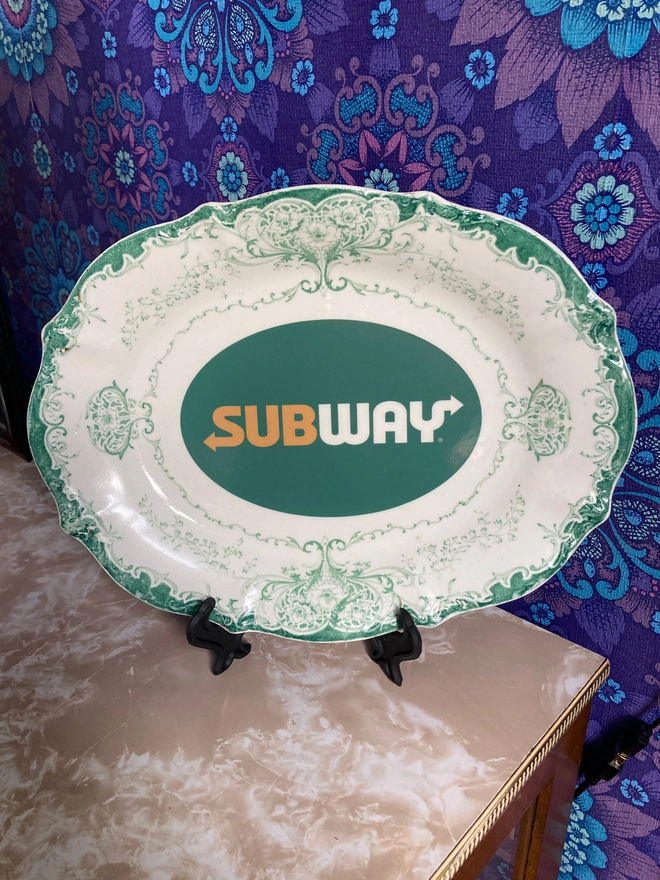 Vintage decorative white and green china plate featuring a Subway logo