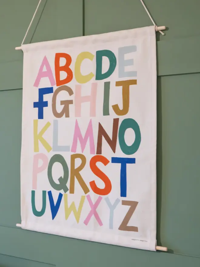 Rainbow Alphabet Fabric Banner, hanging on a green wall. 