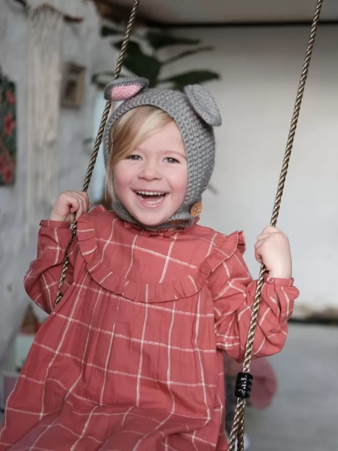 EKA Animal Bonnet seen on a child on a swing.