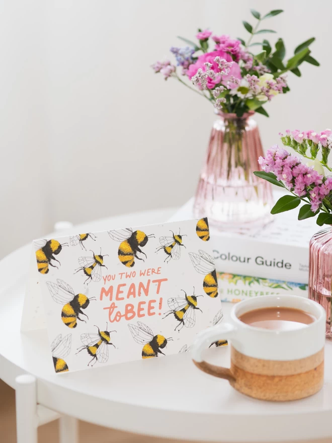 meant to bee plantable wedding card on white table top with vase of wildflowers