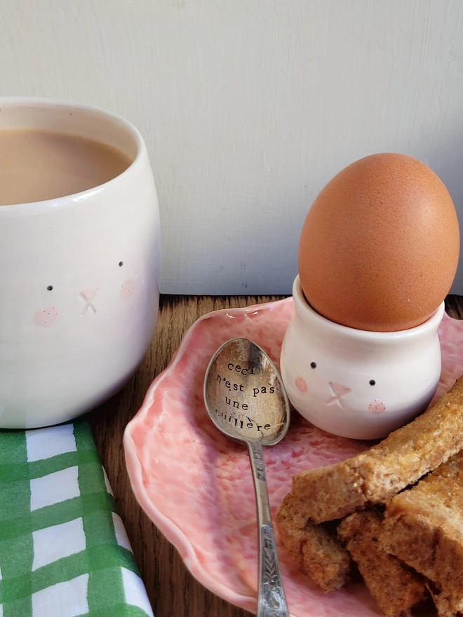 a bunny cup and egg cup on a table with toasted soldiers and eggand egg