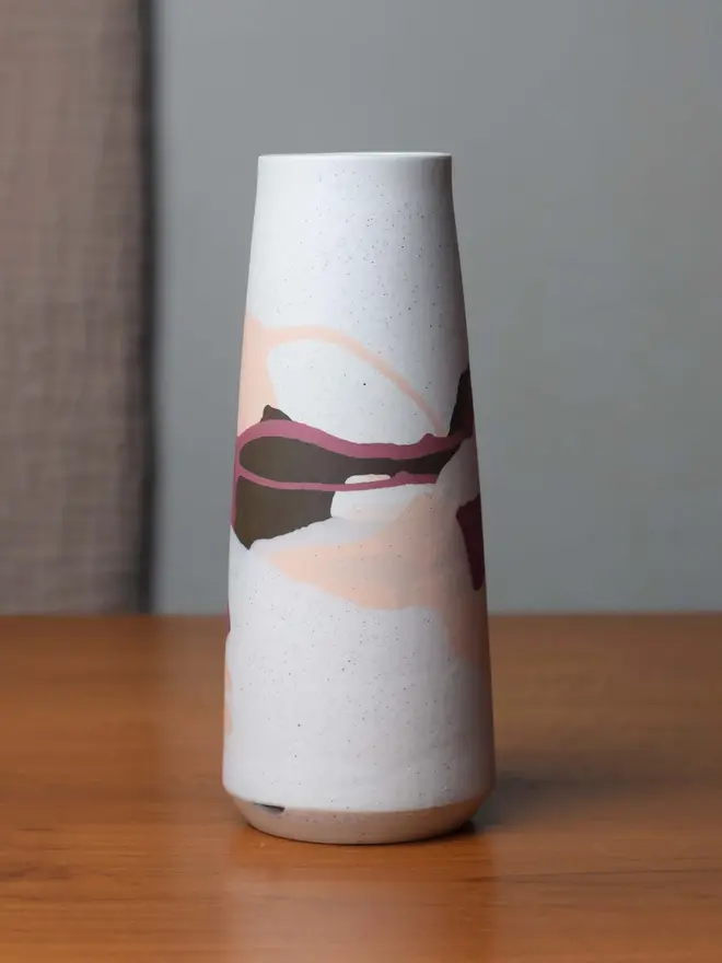 vase on wooden table, vase has streaky pattern in shades of purple, brown, and pale pink