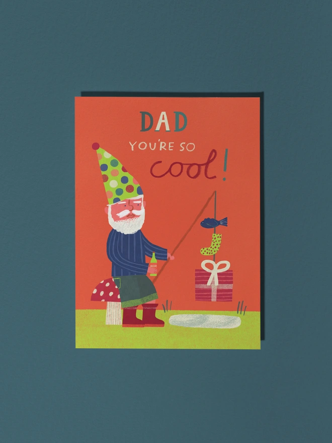 Colourful Gnome Dad sat on toad stool fishing for beer, presents and fish greeting card for birthday and fathers day
