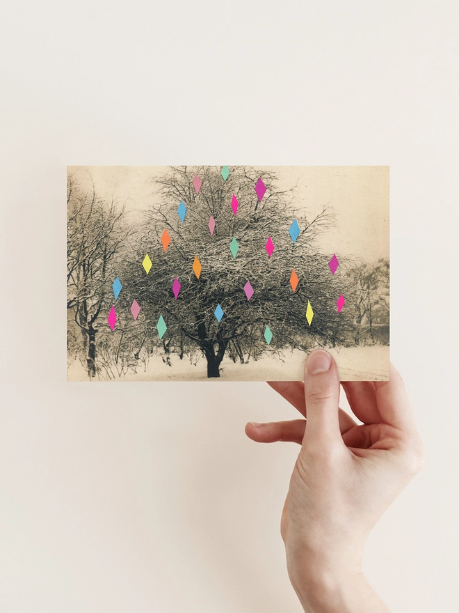 A vintage Christmas card featuring a garden tree covered in diamond shaped baubles.