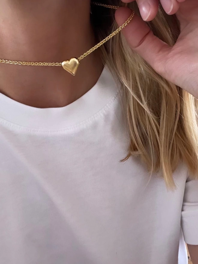 A beautiful simplistic heart of gold on a chain, paired with a minimal white tee