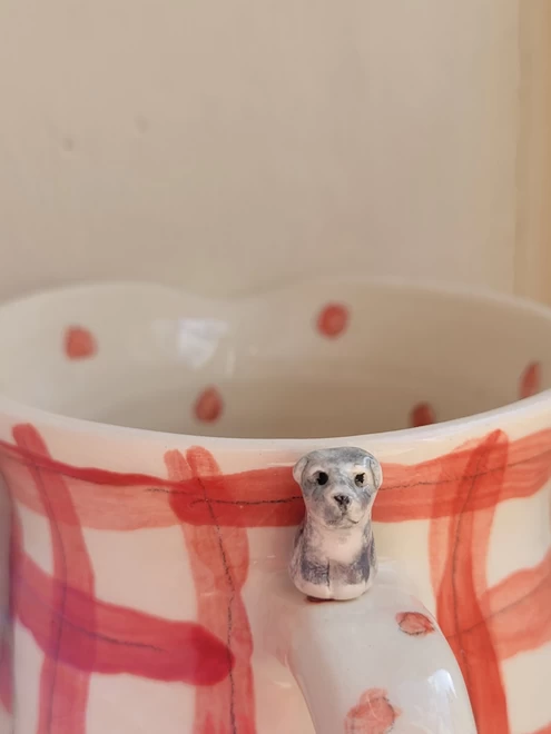 a red check mug with a miniature grey schnauzer dog on the handle