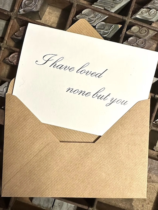 'I Have Loved None But You' Love Card, white Jane Austin card slipping into a brown envelope. 