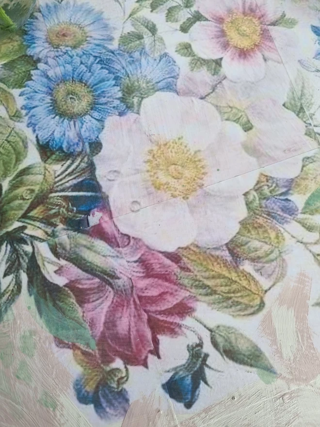 A painted dressing table in white and pale pink with large florals in blues and mauves and text in turquoise that reads 'turn your face to the sun'. The whole piece is distressed in the shabby chic style.