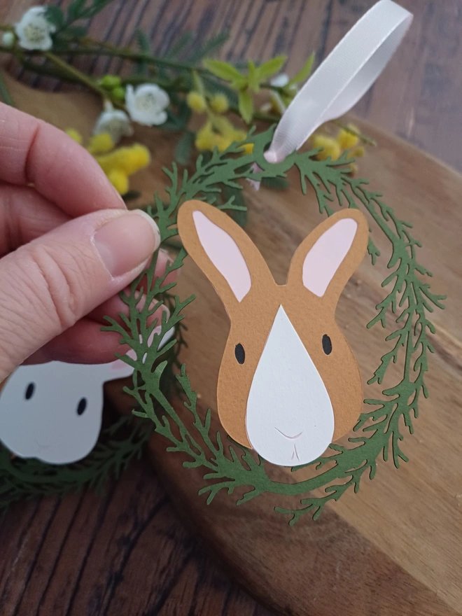 Toffee and White Bunny Decoration held in models's hand above a wooden table